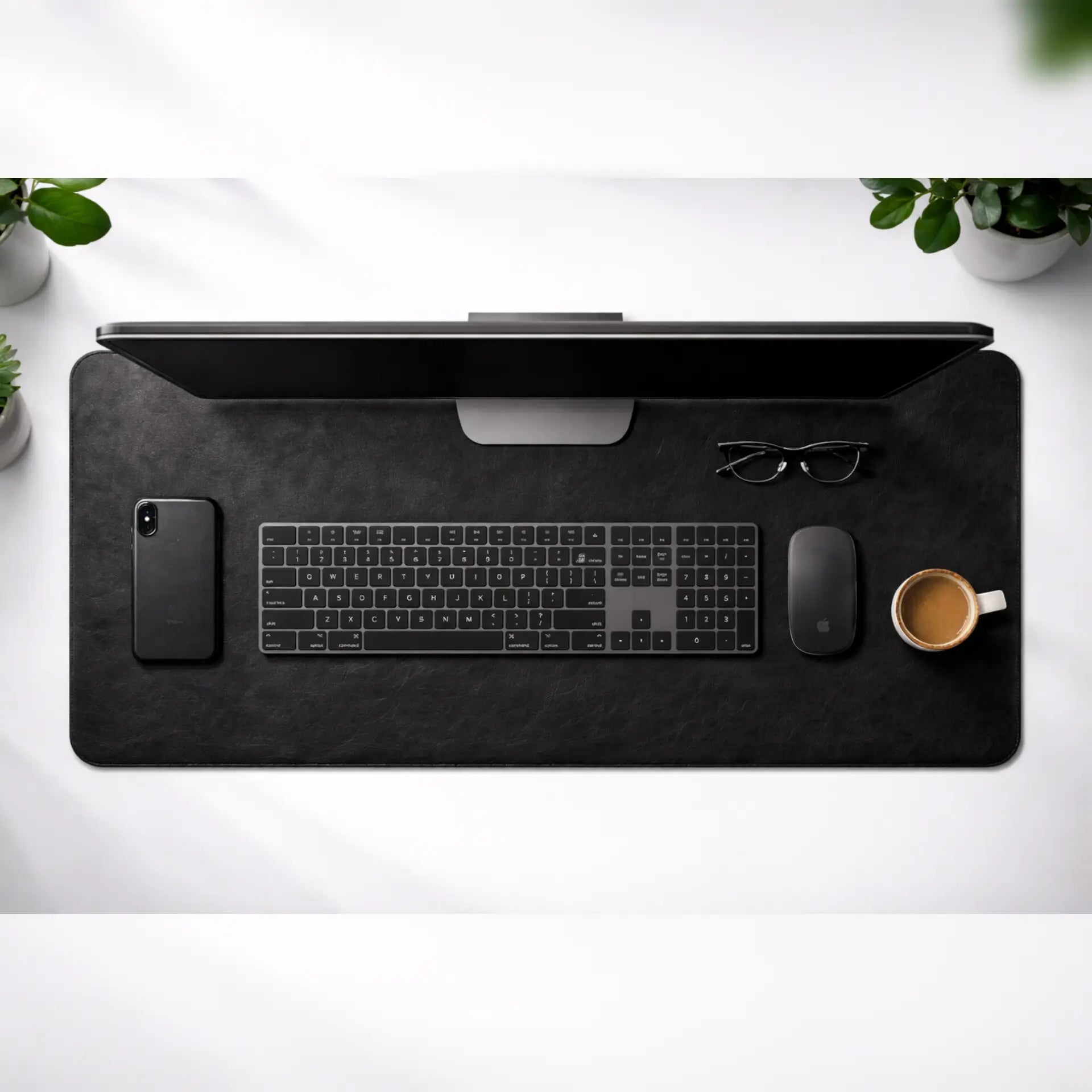 Black desk mat with office items on a white surface