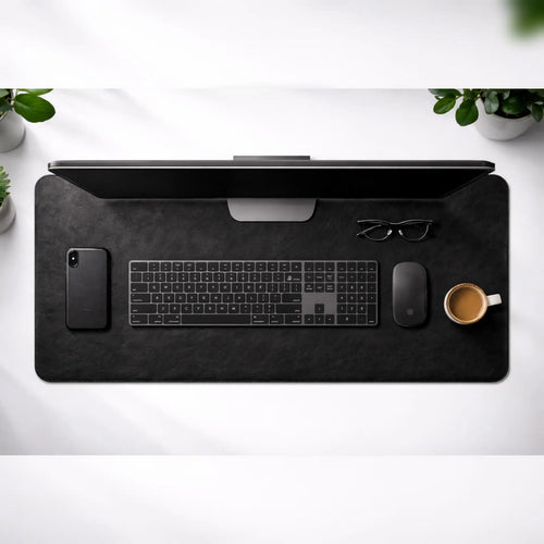 Black desk mat with office items on a white surface