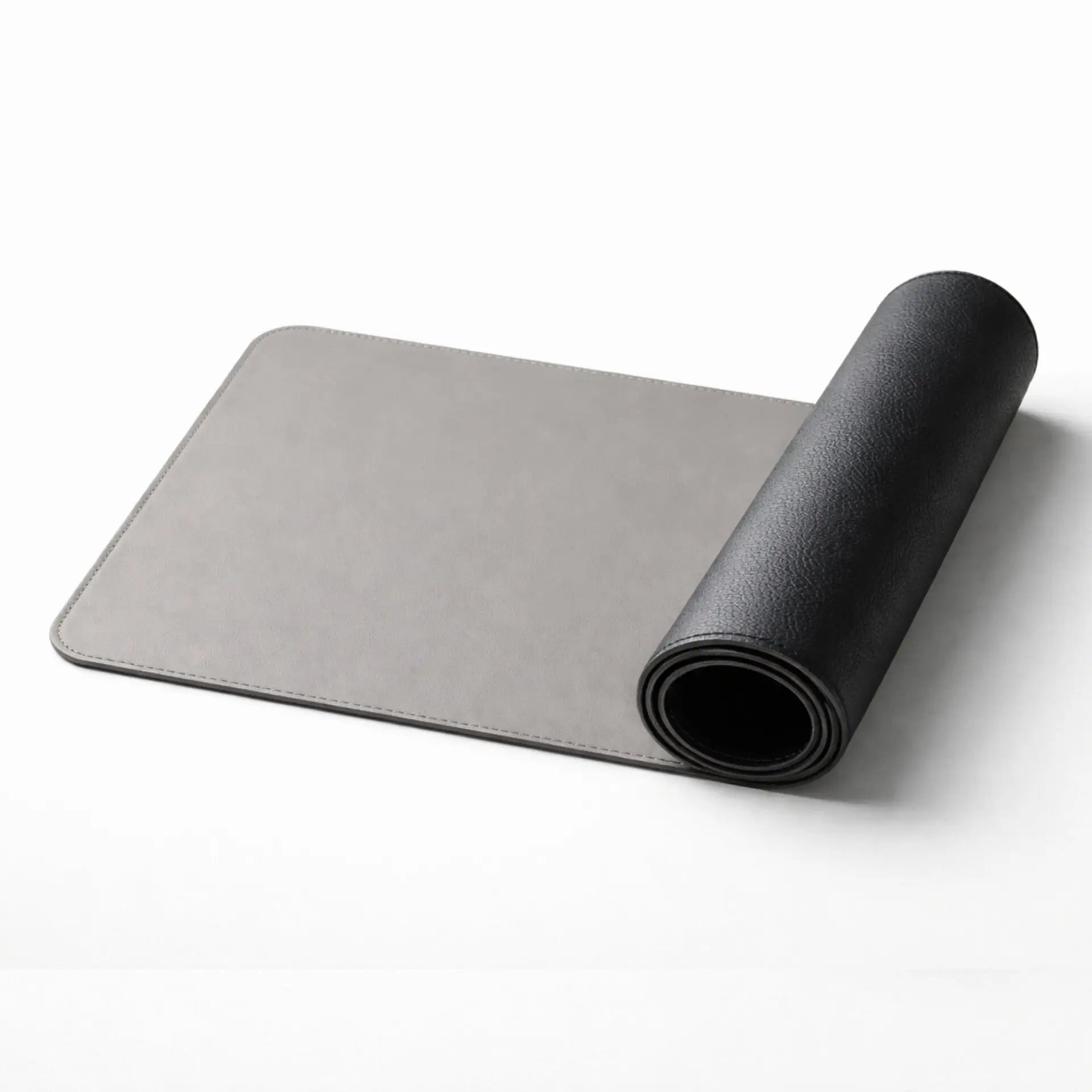 Desdet F50 reversible vegan leather desk mat rolled up showing both midnight black and steel grey sides

