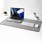 Desdet F50 premium reversible vegan leather desk mat in steel grey with a laptop, keyboard, and coffee cup setup
