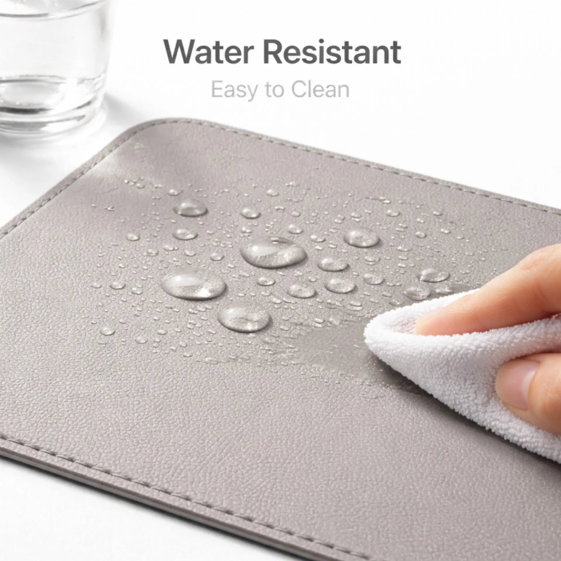 Water resistant surface of Desdet steel grey vegan leather desk mat being wiped clean with a cloth
